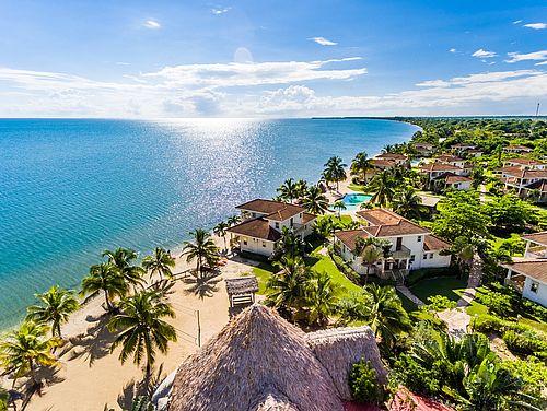 Blick über die Strandhäuser des Hotels Hopkins Bay Resort auf das Meer der Karibikküste Belizes